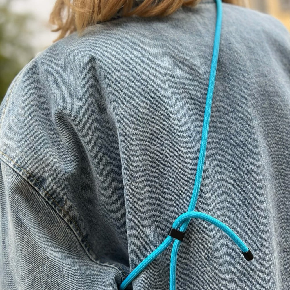 Handykette Neon Blau - Lässig getragen von einer Frau in Jeansjacke